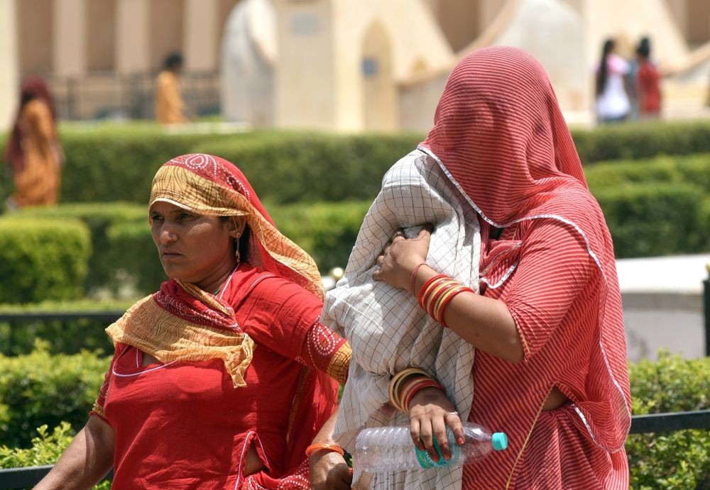 Jaipur: A mother uses a cloth to protect her child from the scorching sun during a hot summer afternoon at historical Jantar Mantar in Jaipur, on Thursday, May 18, 2023. (Photo: IANS/Ravishankar Vyas)