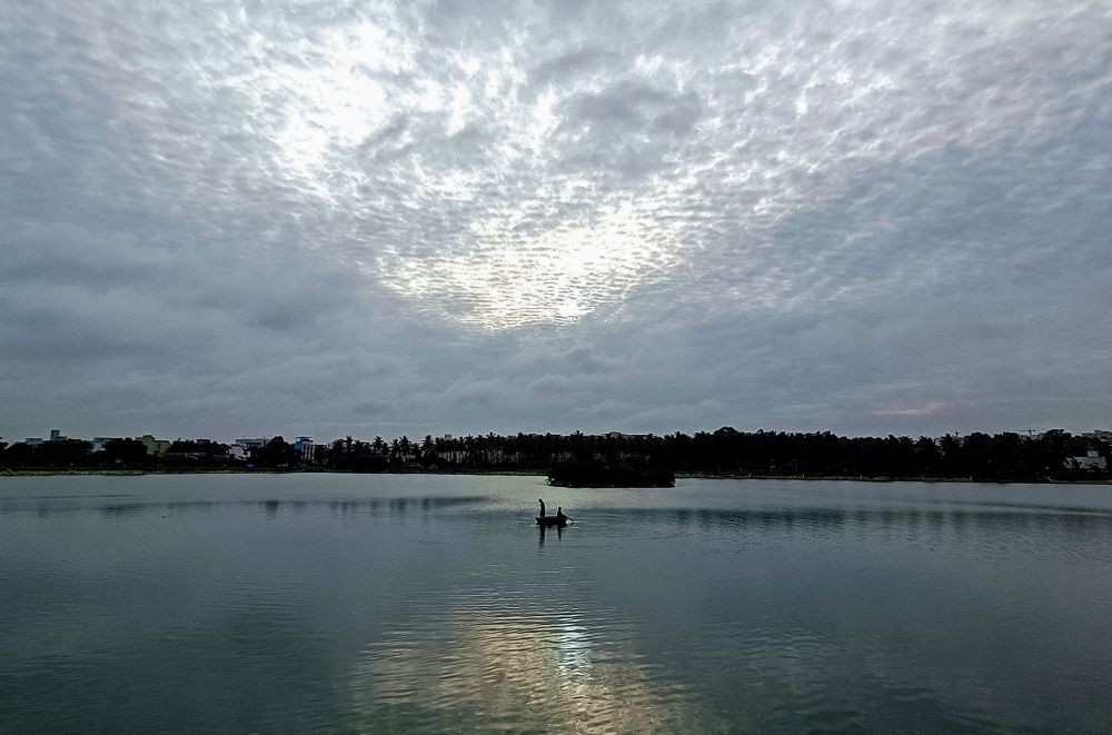 Bengaluru: Fishermen row their boat at Horamavu Lake trying to catch some fish as dark clouds cover the sky at KR Puram, in Bengaluru, on Monday, June 26, 2023. (Photo: IANS/Dhananjay Yadav