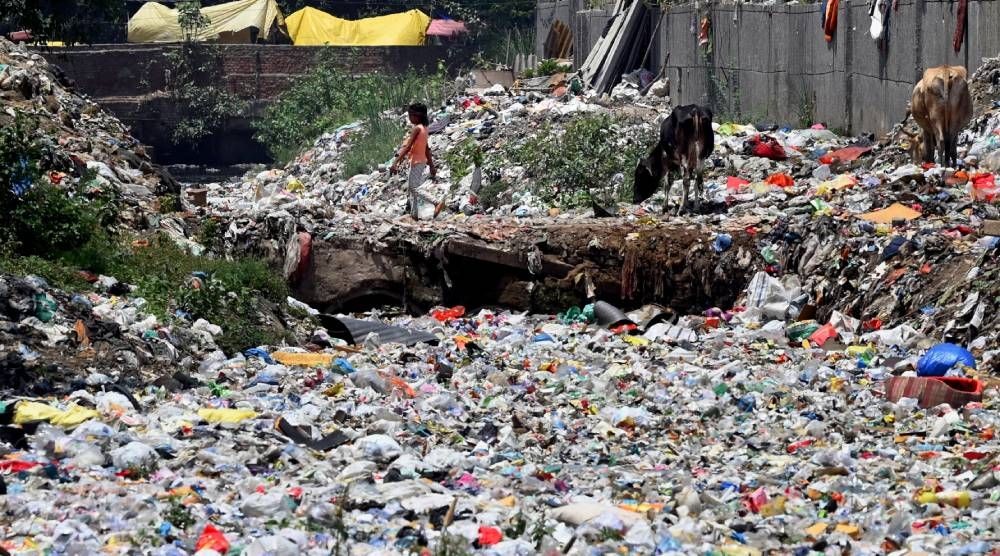 New Delhi: A young girl walks near a blocked drain with a heap of garbage and plastic waste at Taimur Nagar area, in New Delhi, on Monday, June 05, 2023. This picture was taken on the occasion of 'World Environment day'. (Photo: Wasim Sarvar/IANS)