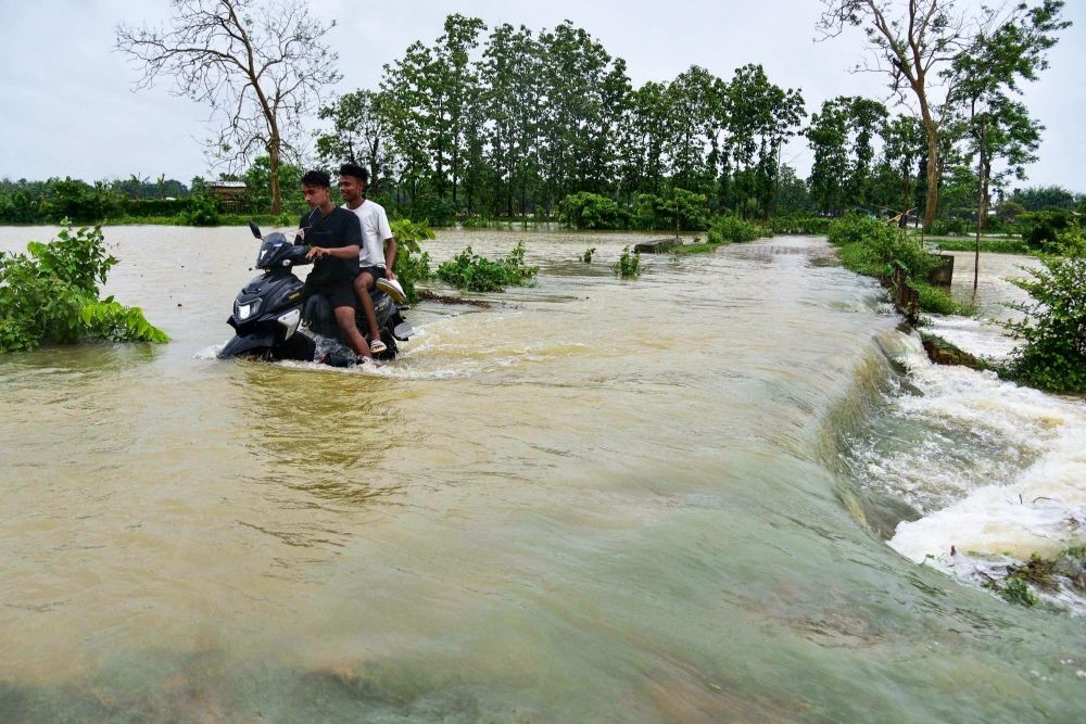 Nagaon : A man rides his two-wheeler as he wades through a flooded road following a heavy rain in Kampur, Nagaon District of Assam on Saturday, June 17, 2023.  (Photo:IANS/Anuwar Hazarika)