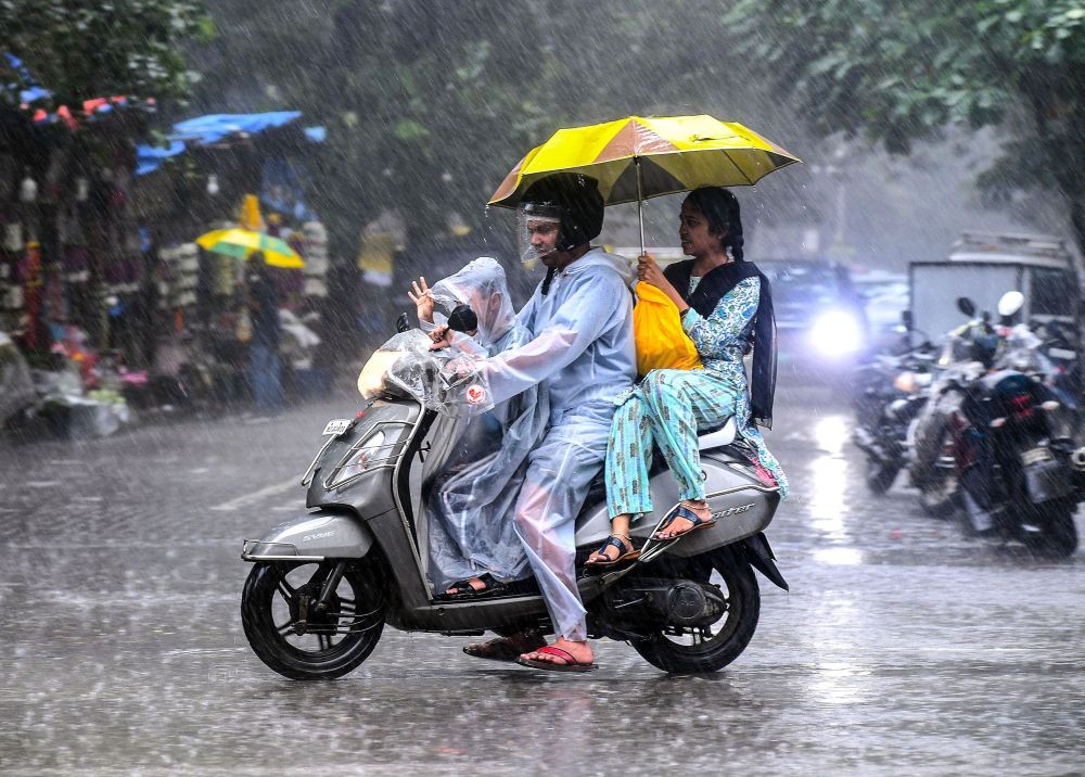 Mumbai: Commuters ride a two-wheeler while holding an umbrella as heavy rainfall lashes, in Mumbai, on Sunday, July 02, 2023. (IANS)