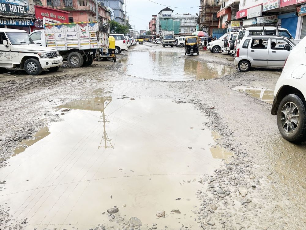 An electric pole and lines are reflected in large craters adorning Golaghat Road near the Blue Hill Bus Station area, Dimapur even as an autorickshaw approaches another, even bigger 'pothole pool' on July 3.  This stretch of the road, located in one of the busiest areas of Dimapur City, is marred by several potholes in the form of big craters. Reportedly repaired last December, the road remains in deplorable condition.