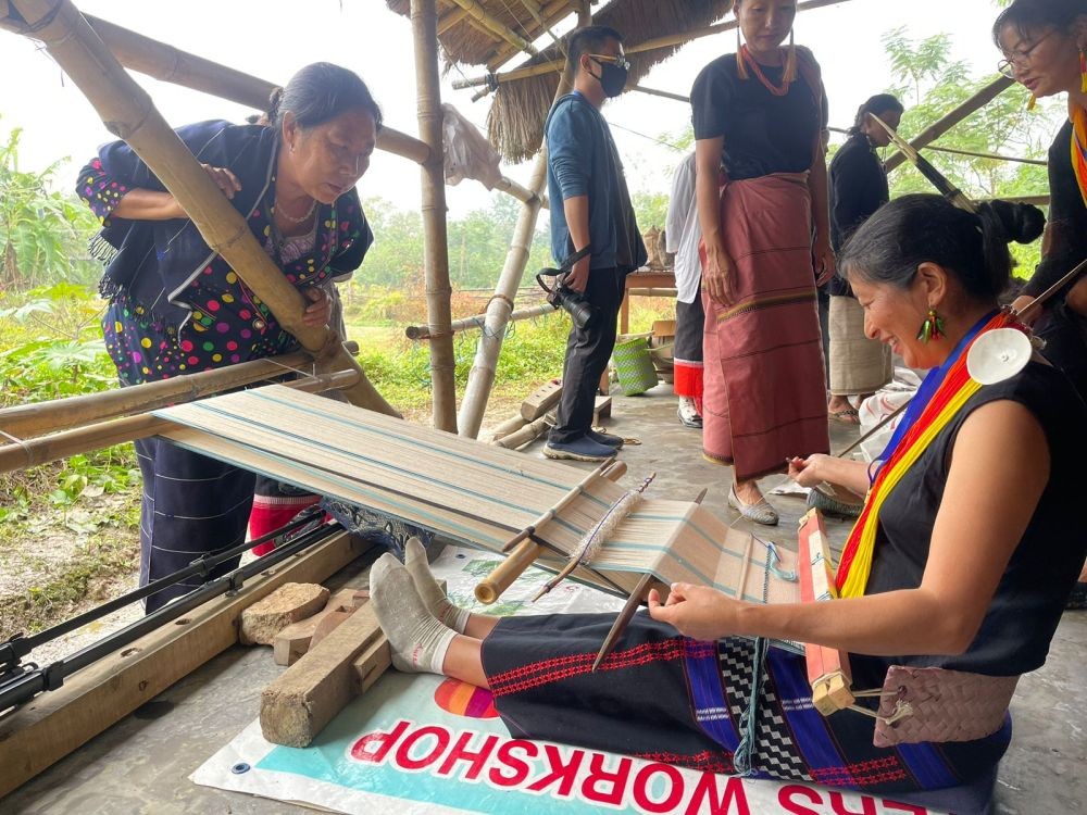 A weaver shares a light moment with an attendee as they discuss the loom techniques before the start of a weaving competition held on the second day of the 9th Naga Loin Loom Festival in Diezephe village on December 7. (Morung Photo)