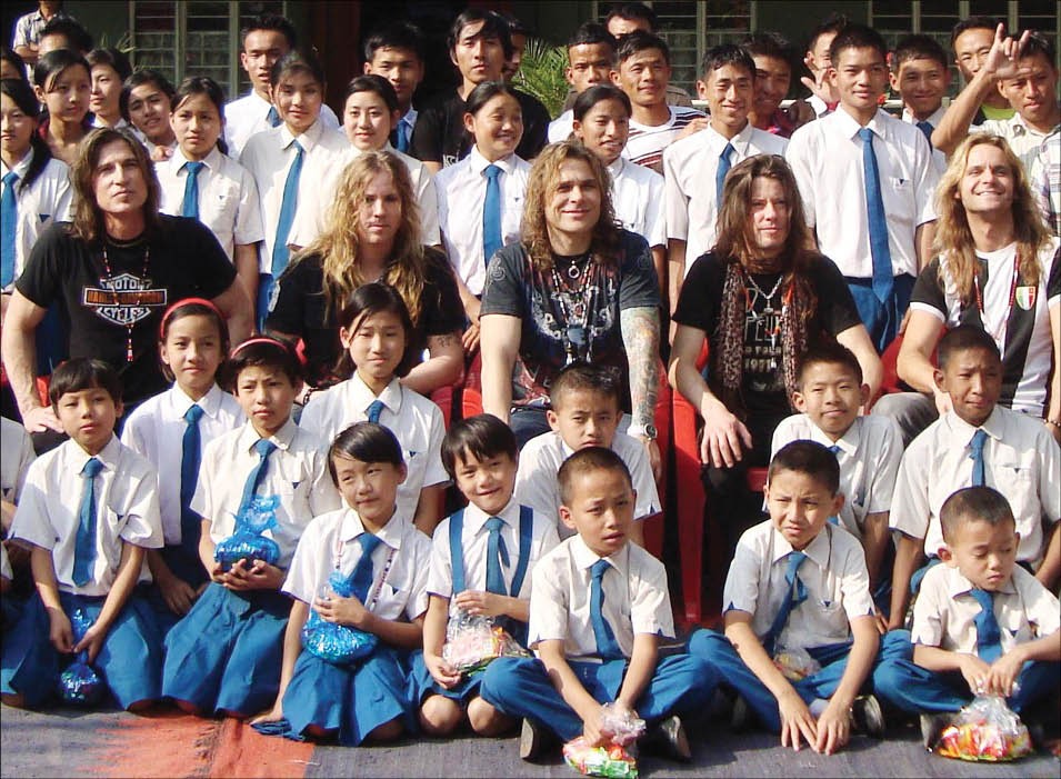 White Lion, with the school children of Deaf & Dumb Biblical Ministry, share a smile at Naharbari village, in Dimapur, on December 15. From left are Bassist EJ Curse, drummer Troy Patrick Farrell, vocalist Mike Tramp, guitarist Jamie Law and keyboardist Henning Wanner. The rock stars will perform Dimapur on the 16th. (Morung Photo/Zakir Hussain)