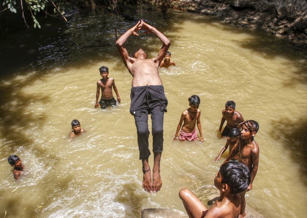 New Delhi: Children take a dip into a pond to beat the scorching heat on a hot summer day, in New Delhi, Monday, May 20, 2024.(IANS/Wasim Sarvar)
