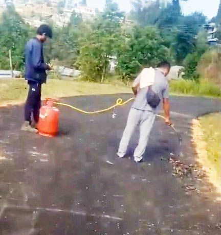 In this screenshot from a video shared on social media on May 13, two people are seen allegedly attempting to burn grasses that had sprouted on a newly constructed road in Chozuba.