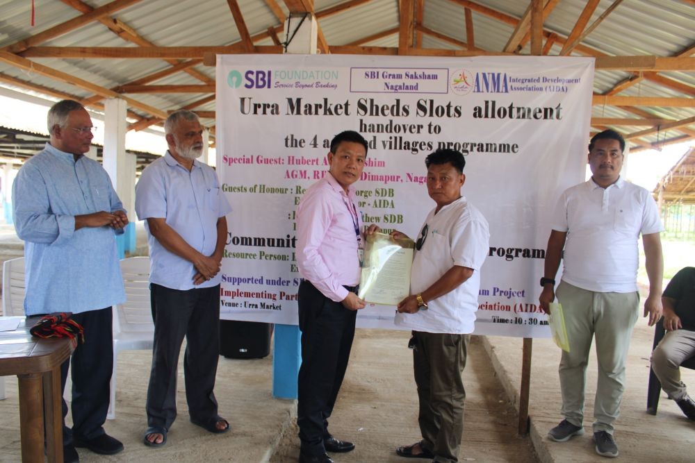 AGM RBO, SBI Dimapur Hubert A S Wungshi handing out allotment of market sheds under SBI Gram Saksham program to a beneficiary in the presence of dignitaries at Chümoukedima on June 25.