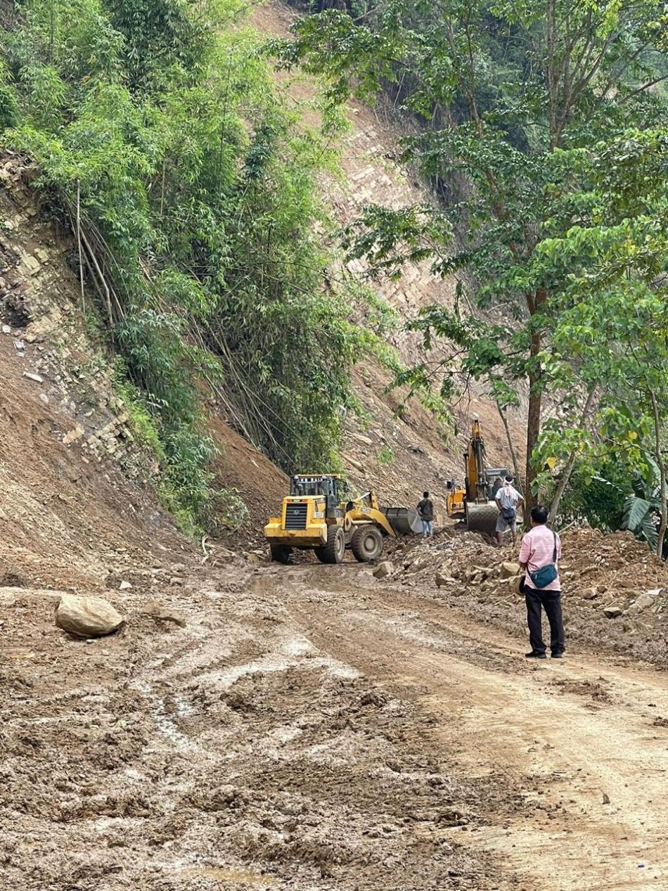 A commuter watches as two excavator clear debris on National Highway 61 (NH-02) between Merangkong and Tuli. The debris was caused by soil-cutting on a landslide-prone hill by an excavator earlier to prevent landslides and rockfalls and as part of ongoing construction works on the stretch. This section, part of the widening project to 2 lanes from Unger to Tuli (Km 185 to Km 220 of NH-61), is listed as 'On-Going Works' in the 2023-24 Annual Administrative Report of the Nagaland Public Works Department. Due to landslides and rockfalls, the road was closed for some period from June 19-23. (Morung Photo)