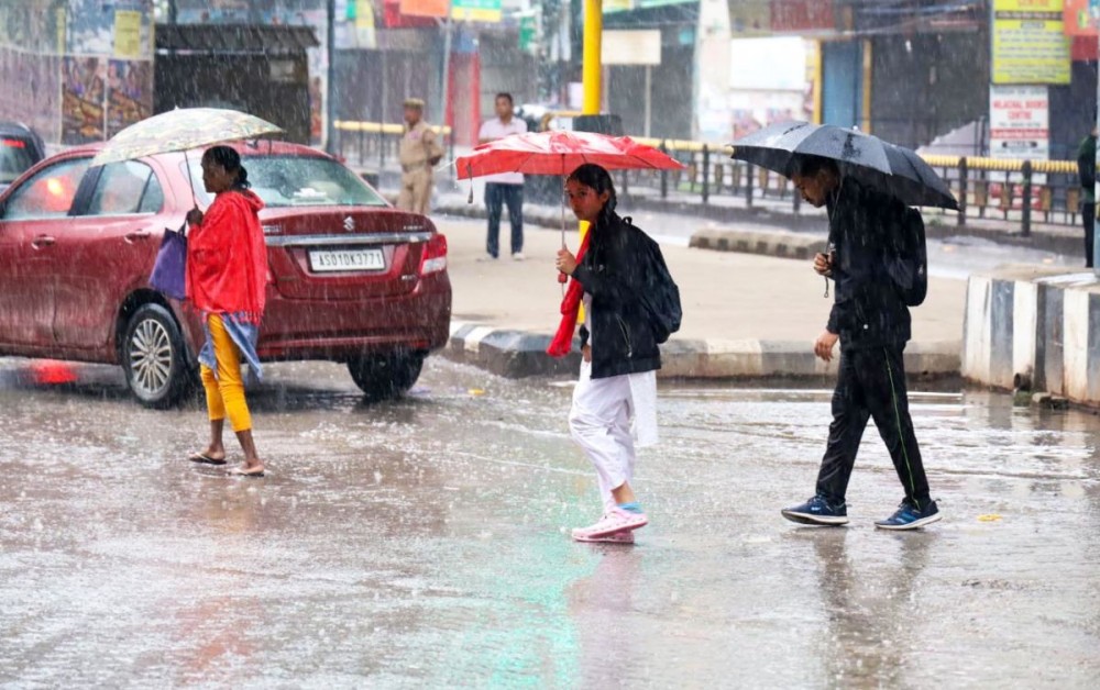 Guwahati : Commuters walk down a pavement during rains in Guwahati on Monday, March 20, 2023. (Photo:IANS/Anuwar Hazarika)
