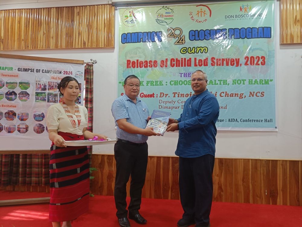 Deputy Commissioner, Dimapur, Tinojongshi Chang (Left), and the AIDA Executive Director, Rev Fr Dr Roy George SDB releasing the Child Led Survey 2023 report at the programme on August 30. (Morung Photo)