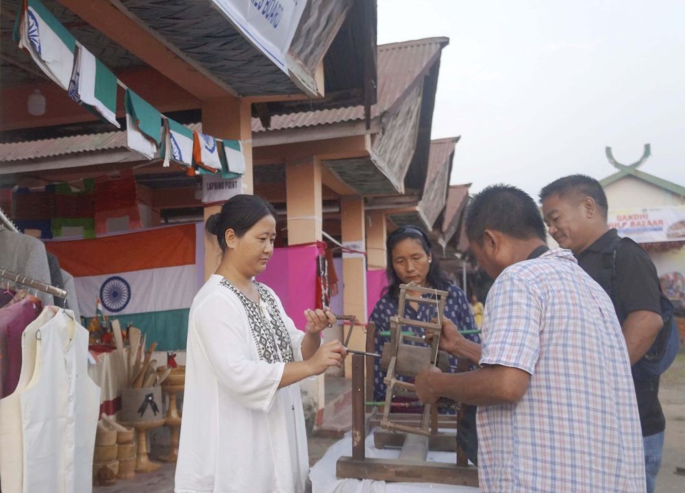 An artisan demonstrates a traditional Charkha as visitors look on, during the Gandhi Shilp Bazar at Urban Haat, which began on October 21. (Morung Photo)