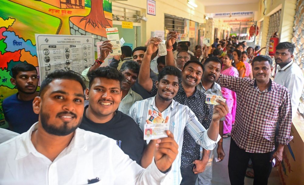 Voters display their identity cards before casting their votes for the Maharashtra Assembly elections in Pune on Wednesday, November 20, 2024. (Photo: IANS/Rahul Deshmukh)