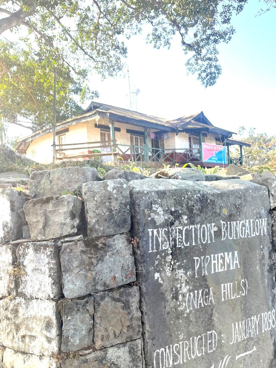 The placard inscribed with the construction date along with the Piphema inspection bungalow in the background. (Morung Photo)
