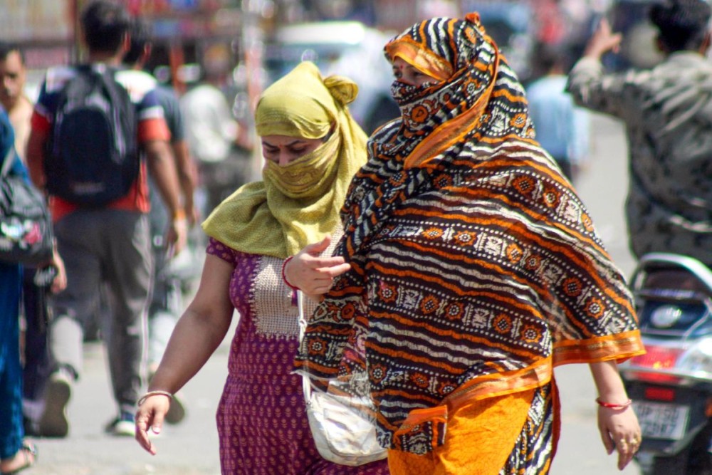 Meerut: Commuters walk past amid scorching heat on a hot summer day in Meerut on Friday, June 7, 2024. (Photo: IANS)
