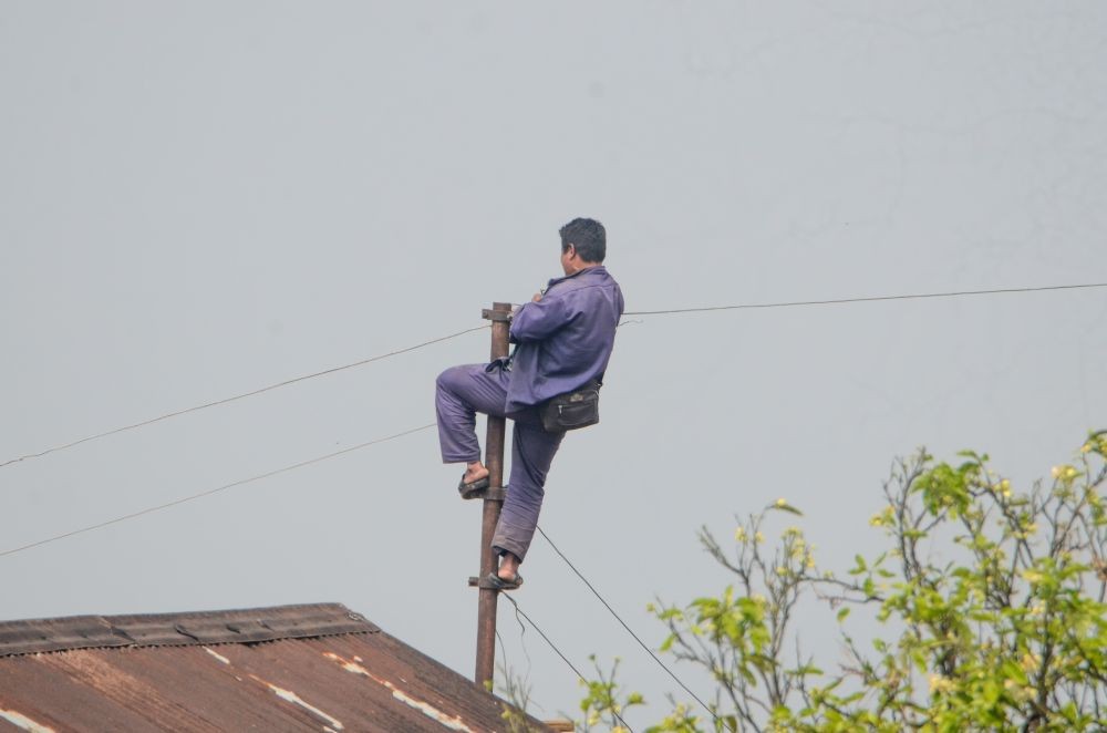 A file photo of an electricity field worker in Nagaland performing maintenance duties under high-risk conditions. (Morung File Photo)