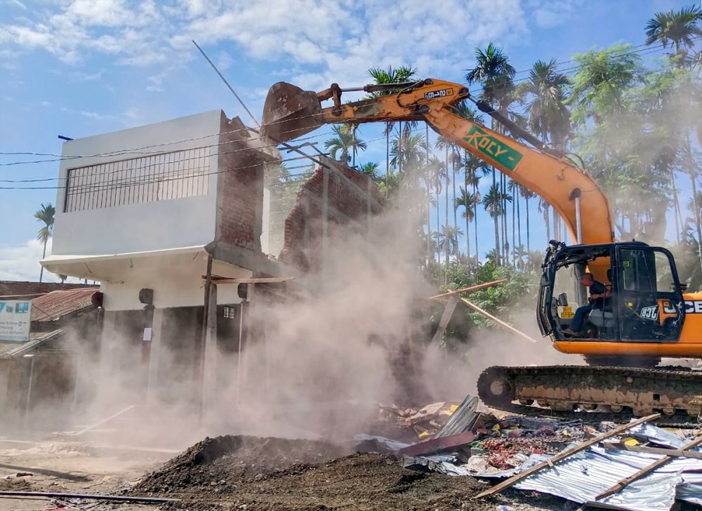 A backhoe loader demolishes structures during an eviction drive by local authorities at an alleged illegal residential settlement inside the Regma forest area at Uriamghat in Golaghat, Assam, on July 29, 2025. (IANS Photo)
