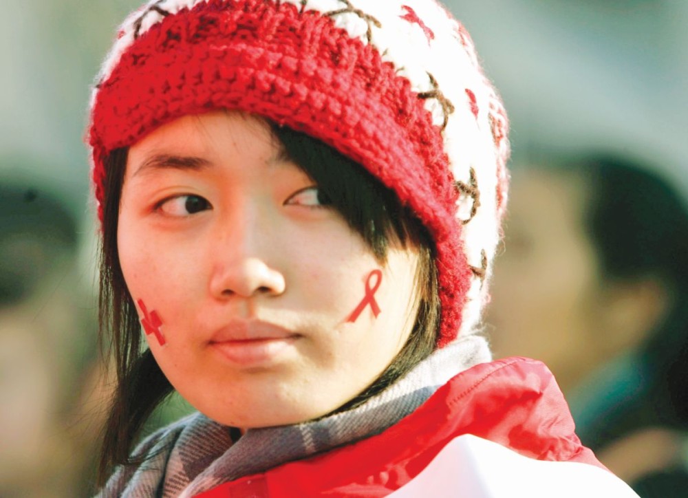A volunteer wears a sticker, a red ribbon, the symbol of AIDS awareness, as  Health authorities and the U.N. AIDS agency  launched a campaign to fight discrimination against people with AIDS in China, at the iconic Bird’s Nest national stadium grounds in Beijing, China, Sunday, November 30. After years of denying that AIDS was a problem, Chinese leaders have shifted gears dramatically in recent years, confronting the disease more openly and promising anonymous testing, free treatment for the poor and a ban on discrimination against people with the virus. (AP Photo)