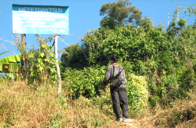 On way for a game or two, a local hunter pauses to read a notice board prohibiting hunting, in Mokochung.