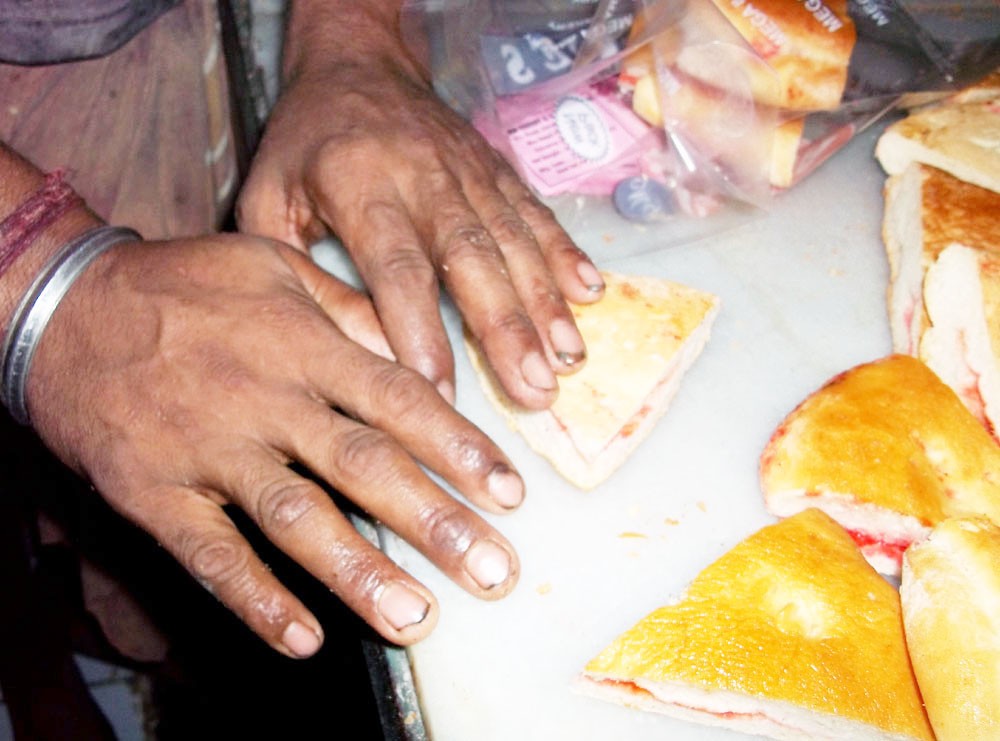 A worker in a bakery packing bakery items with uncut nails and dirty fingers. (Morung Photo)