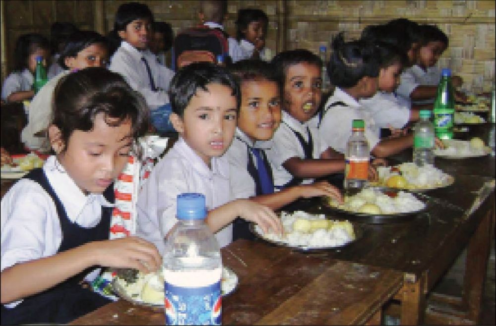 Students enjoy rice served with egg in the midday meal in one of the government schools. (File Photo)