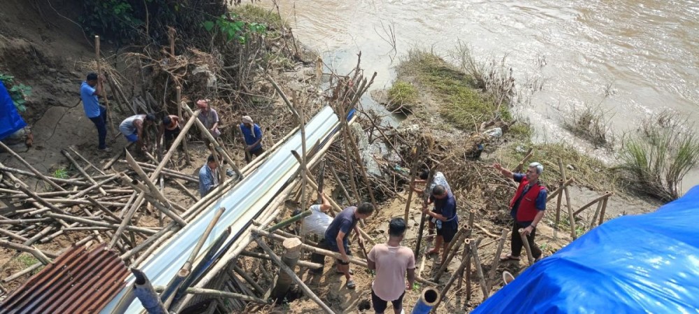 Residents of Kuda Village B-Khel constructing a temporary 70-foot gutter along the Dhansiri River to divert floodwater in Mao Colony.