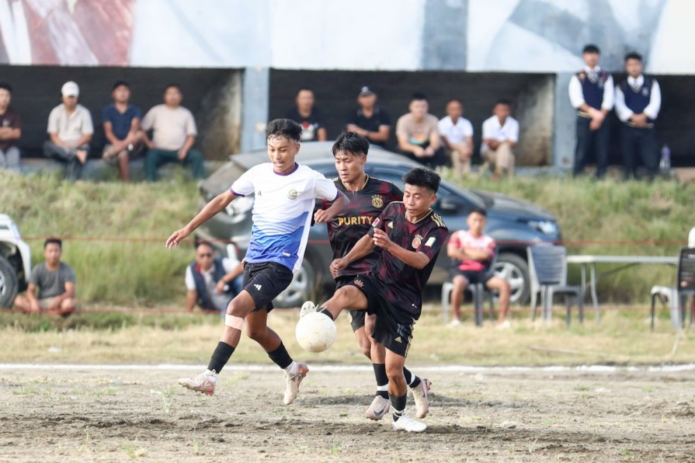 Players of KSUM in white and black jerseys and SSS in black jerseys in action during the opening match of the 27th MDFA Trophy 2025 at Imkongmeren Sports Complex, Mokokchung, on October 14.