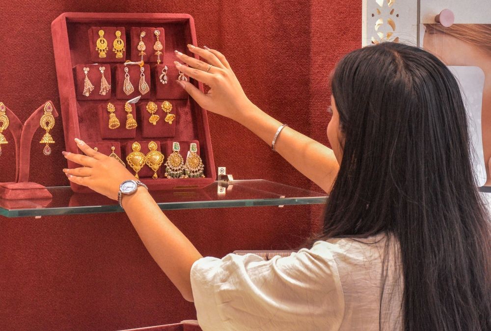 A woman displays gold jewelry at a shop that witnessed low footfall after Prime Minister Narendra Modi urged citizens to adopt cost-cutting measures, including avoiding gold purchases, in Surat on May 12. (IANS Photo)
