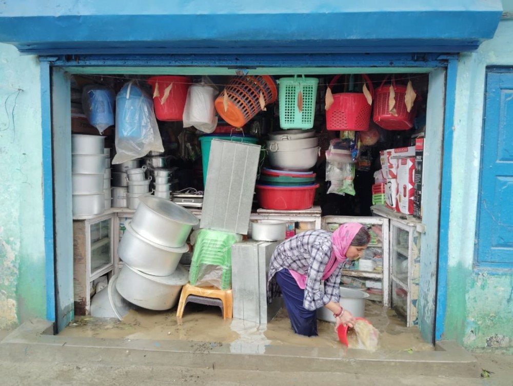 A shopkeeper uses a bucket to drain floodwater from her inundated shop after a sudden afternoon downpour in Zunheboto on May 13.  (Morung Photo)