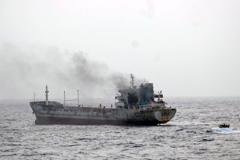 Thick smoke billows from MT Yi Cheng 6 as Indian Navy personnel approach the burning vessel during a firefighting operation on June 29, 2025. (IANS/X/@indiannavy Photo)