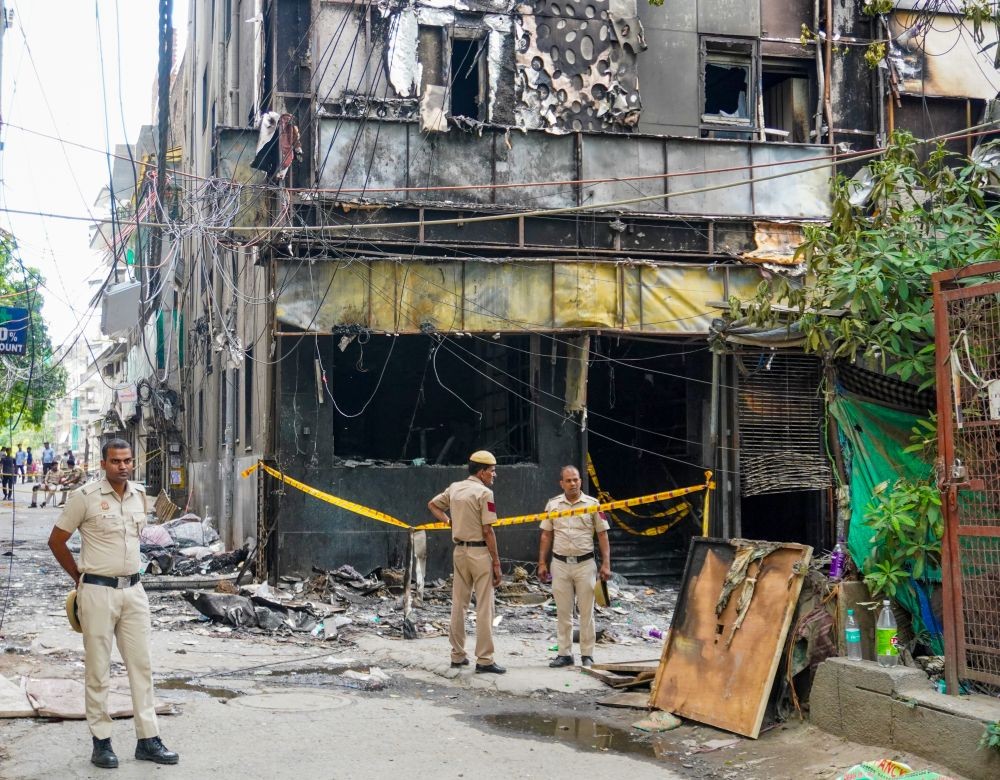 Police personnel stand guard at the site of a devastating fire in a multi-storey building housing a hotel and a restaurant in Malviya Nagar, South Delhi, on June 04, 2026. At least 21 people were killed and several others injured in the incident. (IANS Photo)