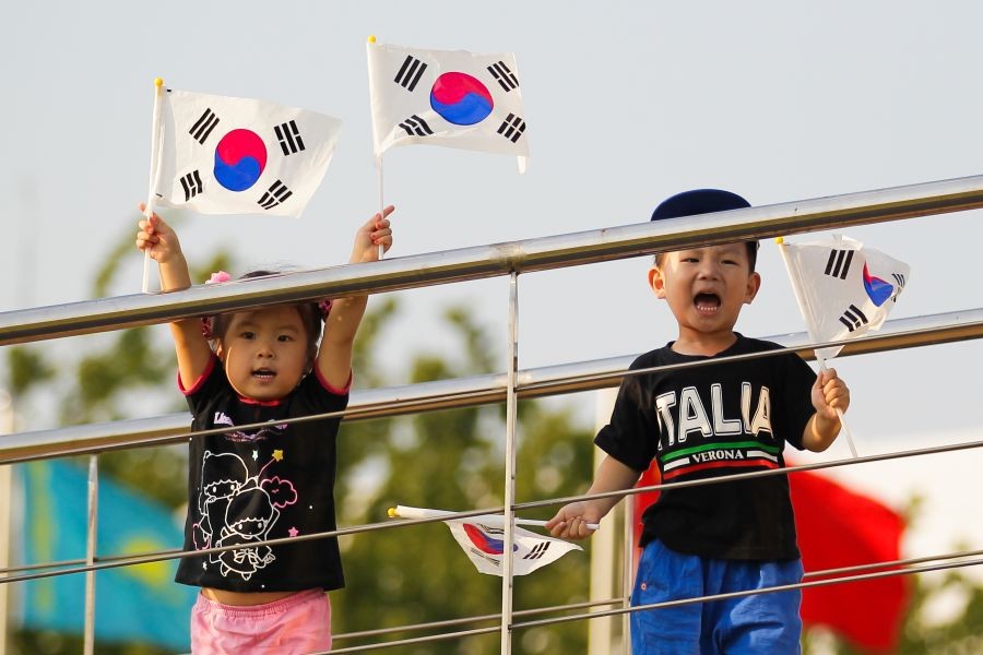 Two children wave the South Korean national flag outside the Incheon Asiad Main Stadium before the opening ceremony of the 17th Asian Games, in Incheon, South Korea. (IANS File Photo)
