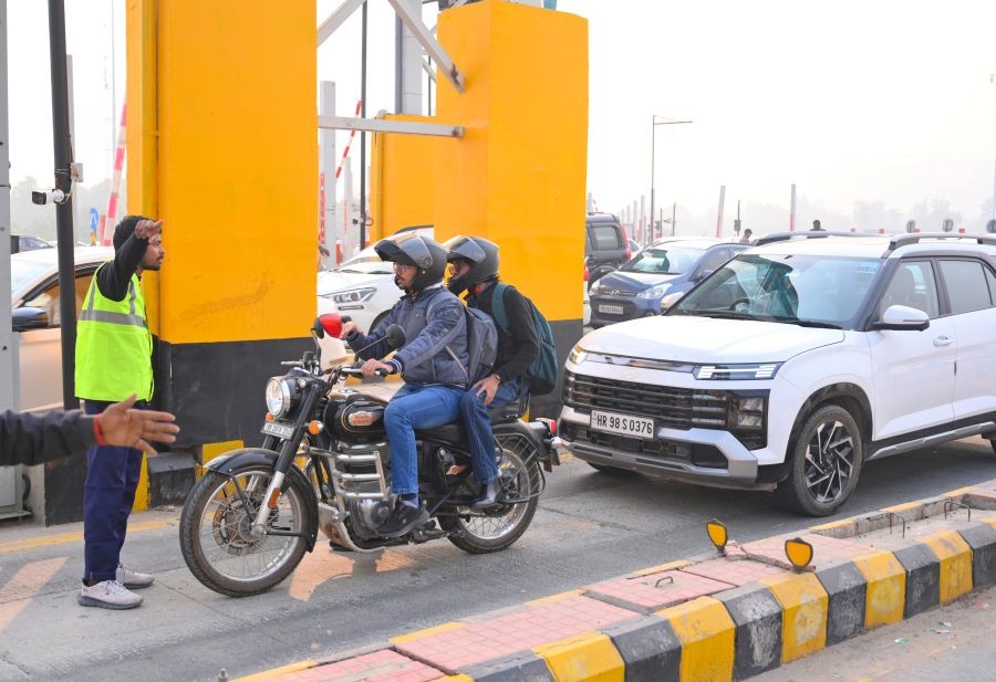 A toll worker guides a motorcyclist after toll collection began on the Dwarka Expressway in Gurugram. (IANS File Photo)