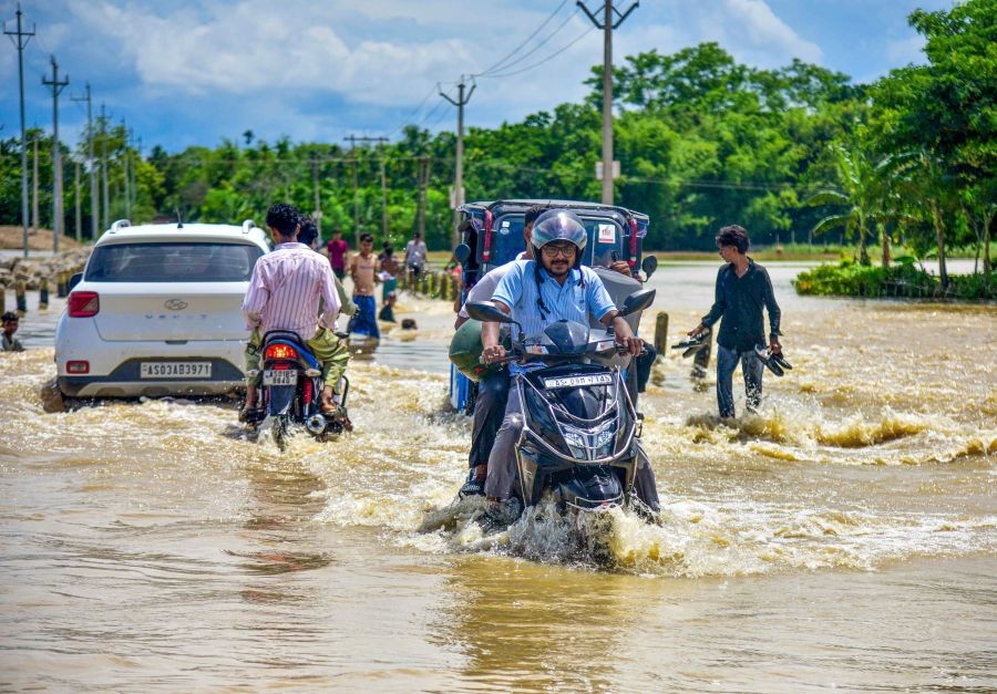 Commuters make their way through a heavily waterlogged road following heavy rainfall in Hojai district of Assam on July 23, 2026. (IANS Photo)