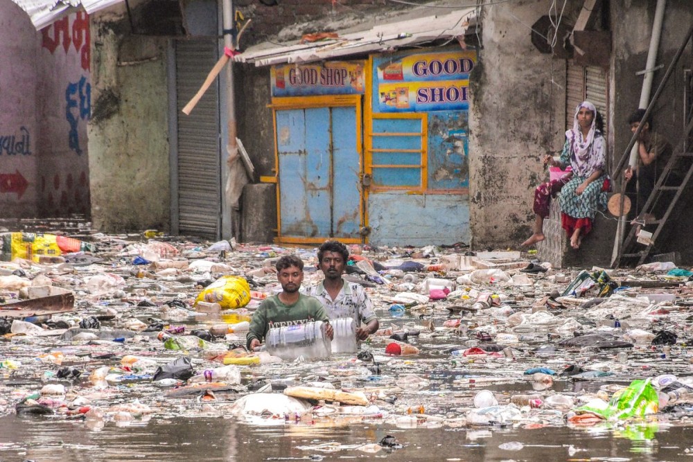 Surat: Residents wade through a waterlogged stretch as garbage floats along the flooded Meethi Khadi area in Limbayat following heavy monsoon rainfall in Surat, Gujarat, on Thursday, July 9, 2026. (Photo: Ashok Munjani)