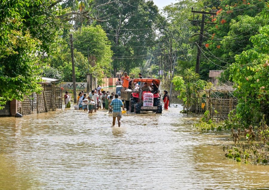 Volunteers distribute relief materials to flood-affected residents using a tractor following heavy monsoon rains in Assam's Sivasagar district on July 27, 2026. (IANS Photo)
