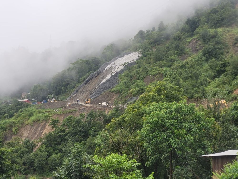 Restoration work continues on a landslide-hit mountain slope amid heavy mist, with excavators and workers engaged in clearing and stabilising the affected stretch. (File Photo)