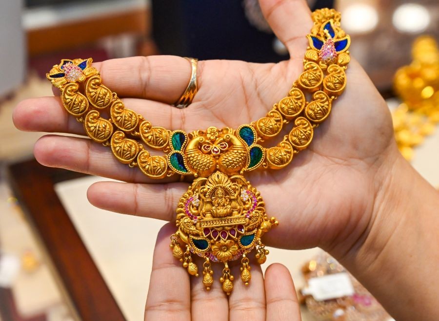 A customer looks at a gold ornament while shopping for gold jewellery on the occasion of Akshaya Tritiya at a jeweller’s shop in Sector 18, Noida on April 19, 2026. (Photo: IANS)